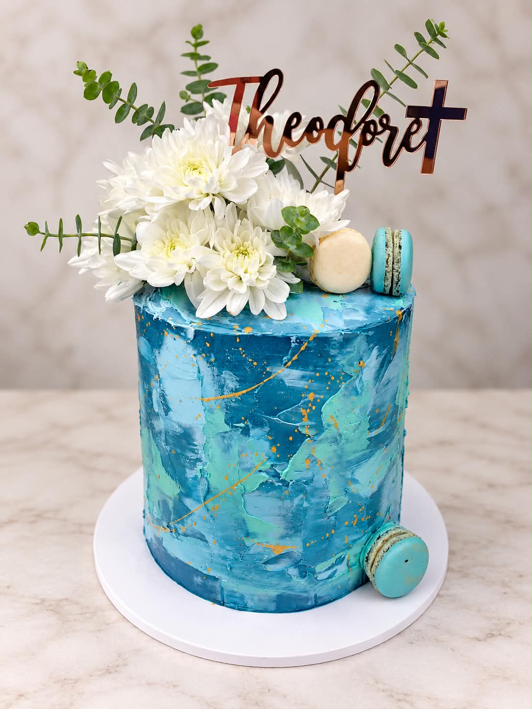 Green and gold custom celebration cake with fresh flowers and macarons